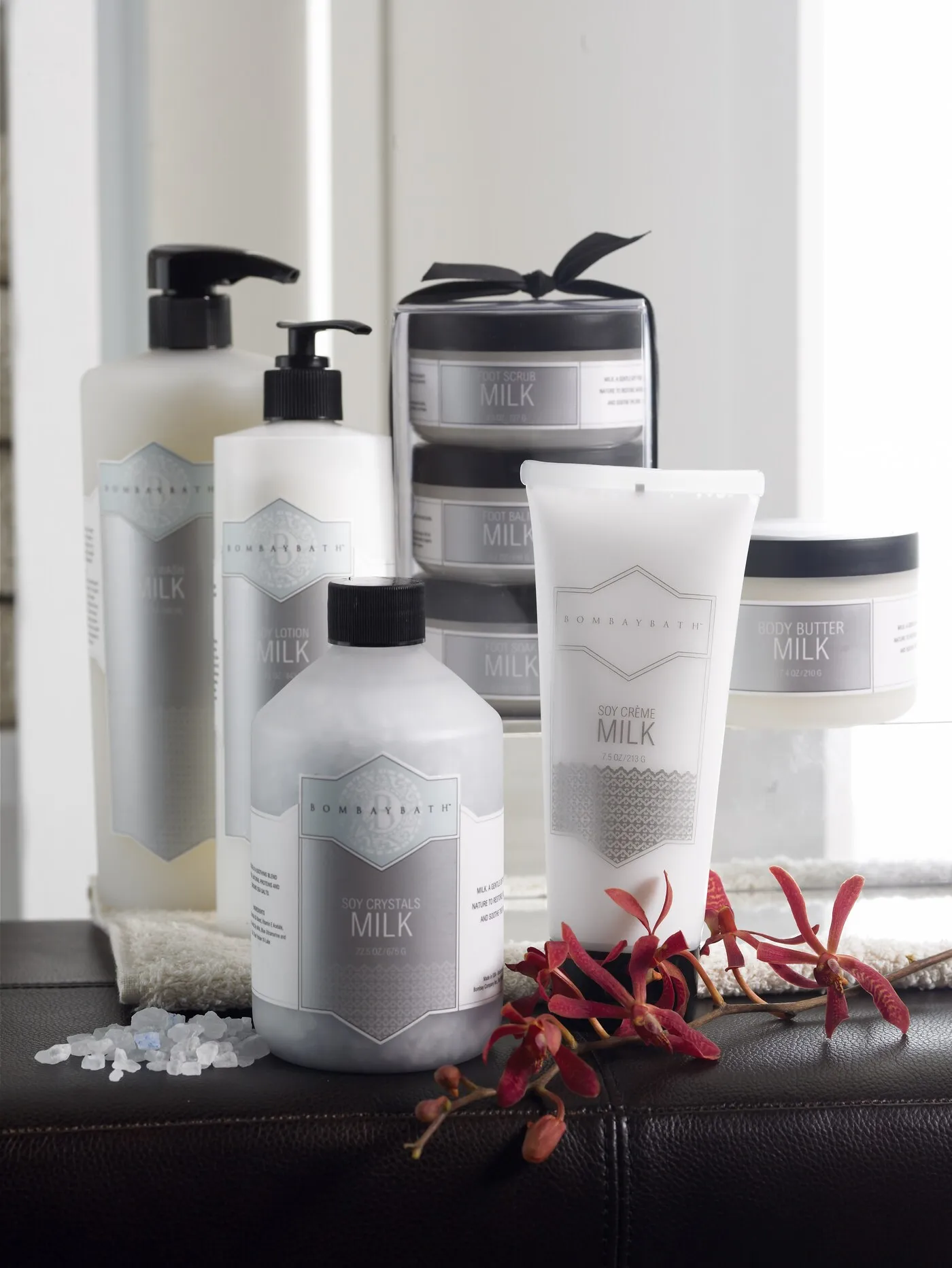 Bombay Bath Milk line packaging arranged with orchids and bath salts.
