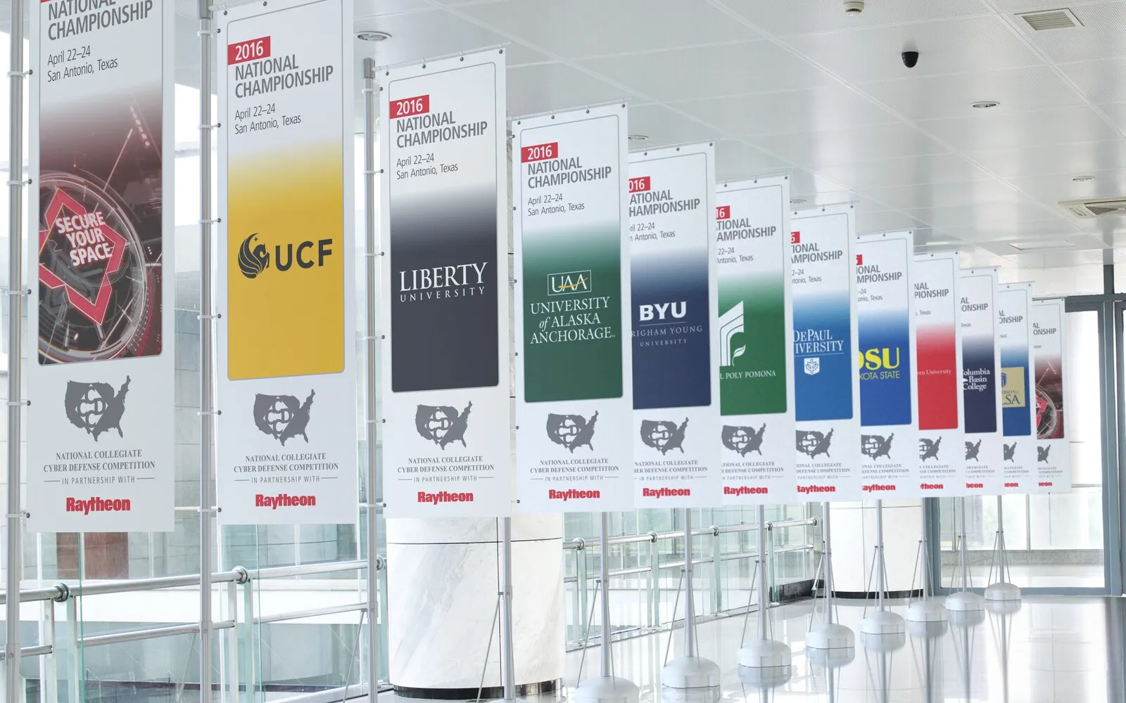 2016 National Collegiate Cyber Defense Championship — a row of university banners in a lobby.